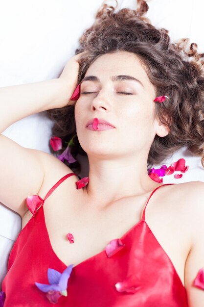 Photo vue haute angle d'une belle femme allongée avec des pétales sur le lit