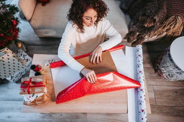 Photo vue haute angle d'une femme emballant un cadeau de noël à la maison