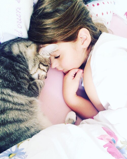 Photo vue haute angle d'une fille qui dort avec un chat sur le lit à la maison