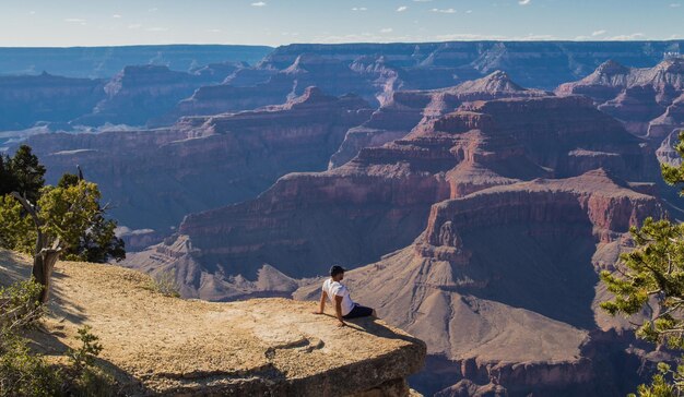 Vue haute angle de l'homme assis sur la falaise contre le canyon