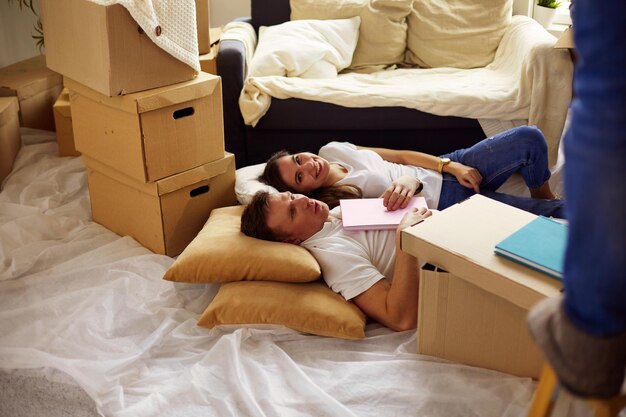 Vue en hauteur d'un couple heureux allongé sur le sol avec beaucoup de boîtes