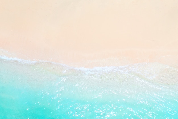 Une vue d'une hauteur d'une plage tropicale et des vagues se brisant sur une plage tropicale de sable doré. Les vagues de la mer serpentent doucement le long de la belle plage de sable.