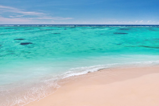 Une vue d'une hauteur d'une plage tropicale et des vagues se brisant sur une plage tropicale de sable doré. Les vagues de la mer serpentent doucement le long de la belle plage de sable.