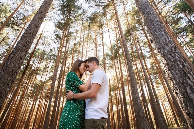 Vue horizontale du jeune couple en randonnée en vacances dans la nature. Vue panoramique d'un couple d'amoureux s'embrassant au coucher du soleil dans la forêt. Concept de voyage et de personnes à la campagne.