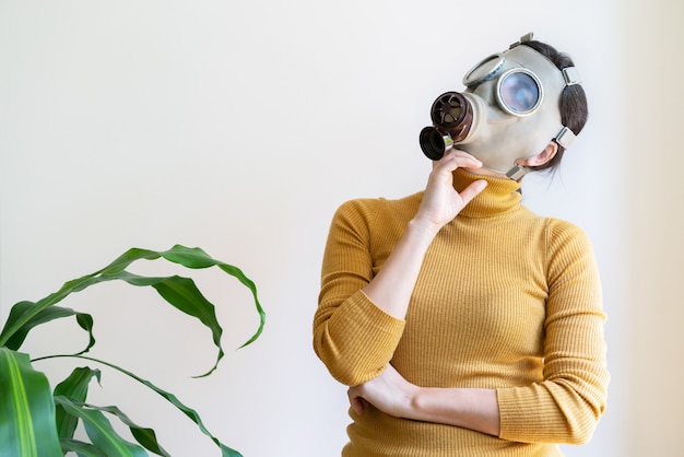 Vue horizontale de femme avec masque à gaz entouré de plantes à la maison isolé sur blanc