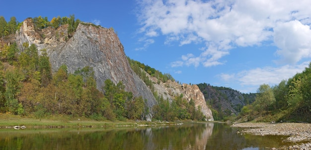 Une vue imprenable sur un rocher majestueux éclairé par la lumière du soir sur une rivière rapide par une belle journée