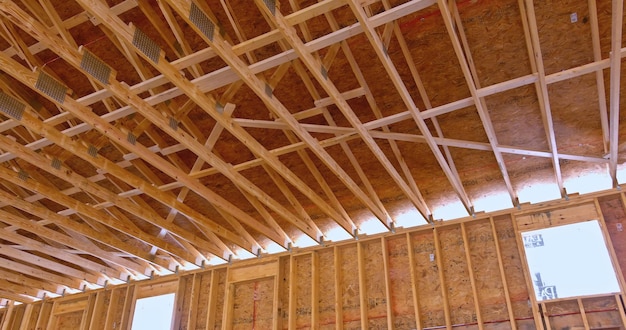 Vue de l'intérieur de la construction d'une nouvelle maison avec des fermes de toit en bois à ossature apparente