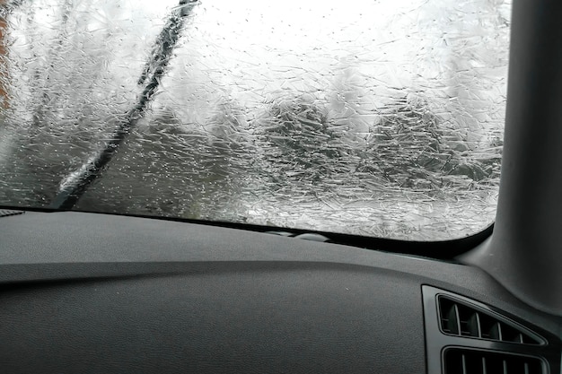 Vue à l'intérieur de la vitre de la voiture miroir pare-brise recouvert de glace gelée journée froide d'hiver