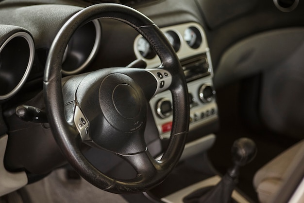 Vue de l'intérieur d'une voiture avec le tableau de bord et le volant au premier plan