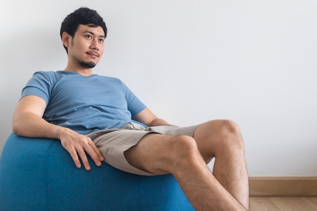 Vue des jambes de l'homme sur un lit blanc avec TV et plante. Concept de détente.