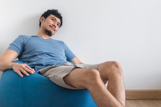 Vue des jambes de l'homme sur un lit blanc avec TV et plante.