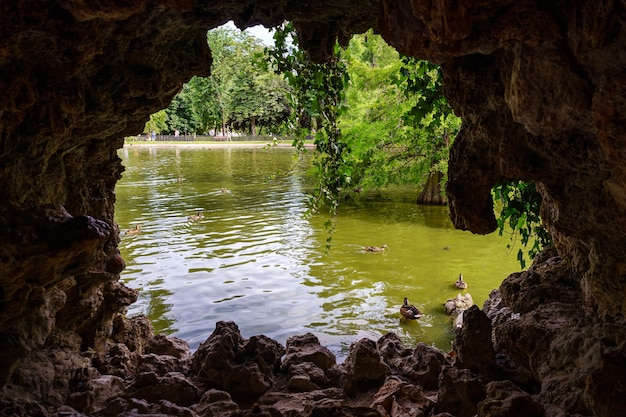 Vue sur lac avec canards et végétation depuis une grotte rocheuse. Le Retiro Madrid.