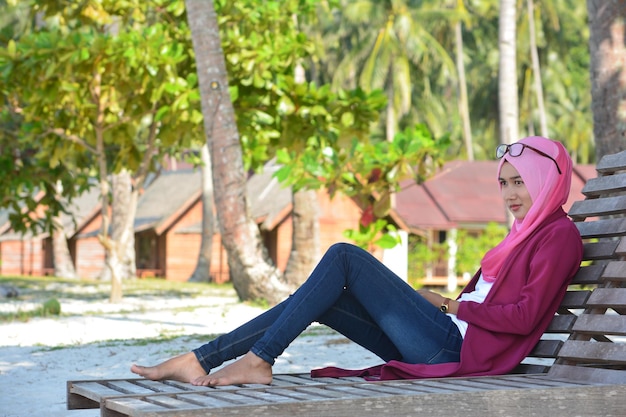 Photo vue latérale d'une belle femme assise sur une chaise en bois sur la plage