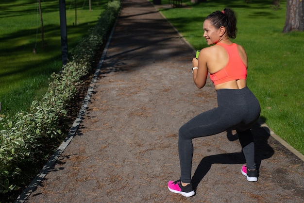 Vue latérale de la belle jeune femme en tenue de sport, faire des exercices de squat