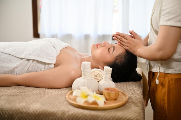 Vue latérale Calme femme asiatique allongée sur une table de massage se faisant masser Spa thaï Massage thaï
