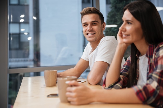 Vue latérale des collègues assis près de la table avec un café au bureau.