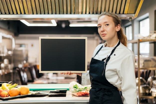 Vue latérale du chef féminin posant dans la cuisine