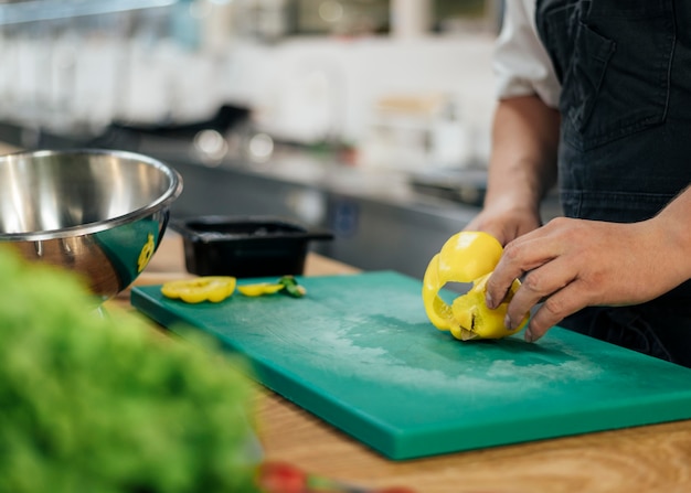 Photo vue latérale du chef avec tablier de coupe de poivron