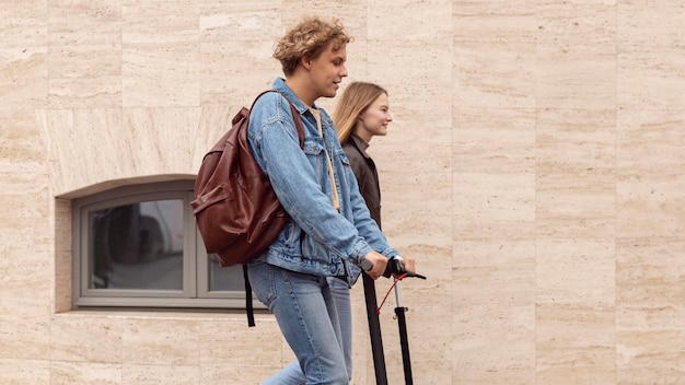 Vue latérale du couple à l'aide de scooters électriques dans la ville