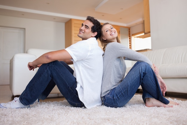 Vue latérale du couple assis sur le tapis dos à dos