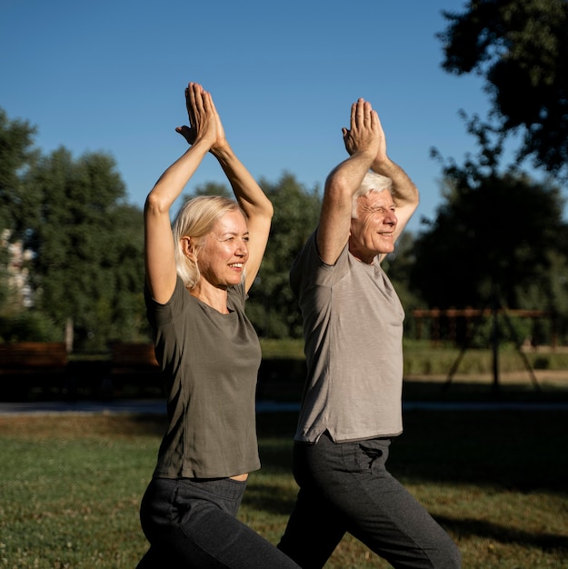 Photo vue latérale du couple de personnes âgées faisant du yoga à l'extérieur