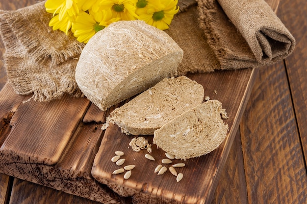 Vue latérale du halva, dessert sucré oriental fait de graines huileuses d'arachide broyées en une pâte et mélangées avec du sirop de sucre servi sur un bureau en bois avec des fleurs.