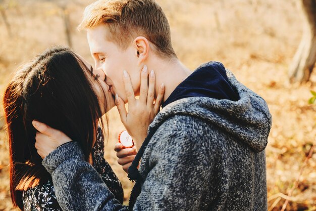 Vue latérale du jeune homme et femme s'embrassant après proposition sur une journée ensoleillée dans la nature