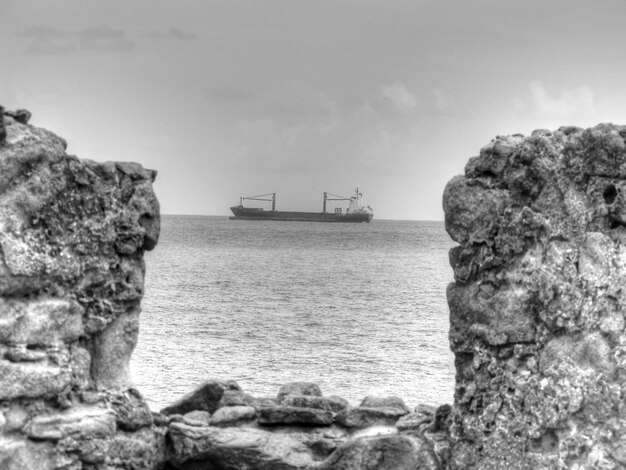 Photo vue latérale du navire au loin avec un mur rocheux au premier plan