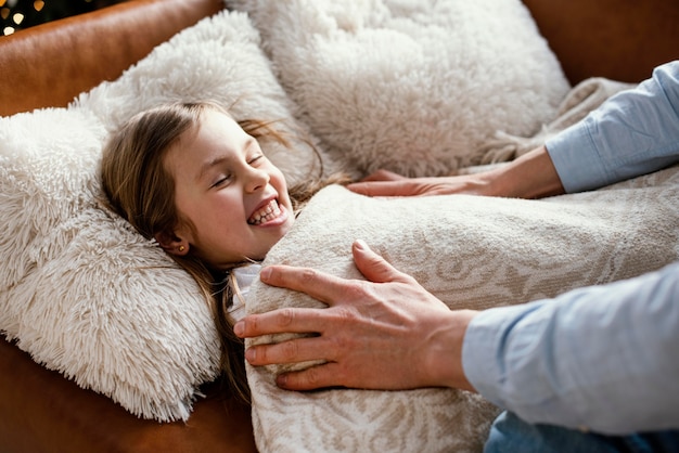 Vue latérale du père rentrant sa fille au lit