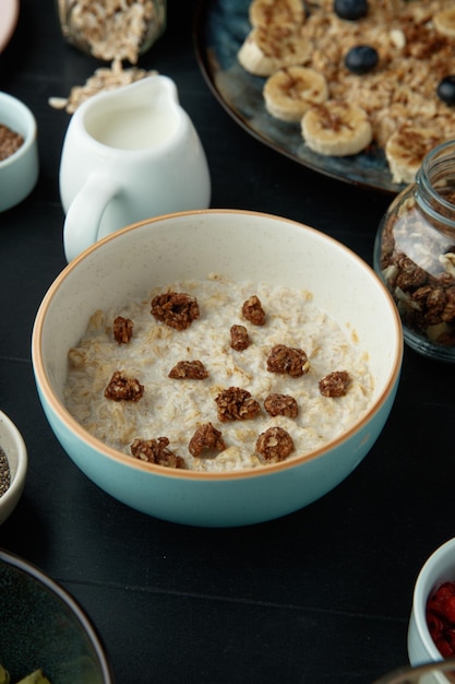 Vue latérale du petit-déjeuner avec bol de flocons d'avoine aux noix et lait aux noix sur fond noir