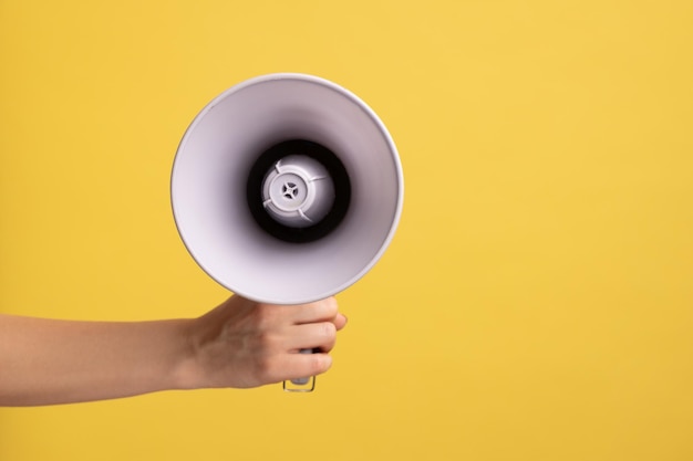 Vue latérale du profil gros plan de la main de la femme tenant le haut-parleur mégaphone pour annoncer la publicité