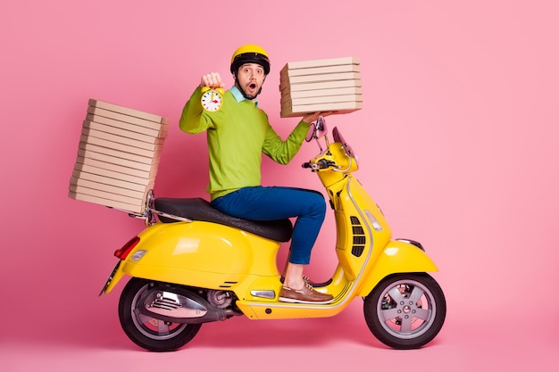 Vue latérale du profil portrait de gars conduisant un cyclomoteur tenir horloge boîtes à pizza pile