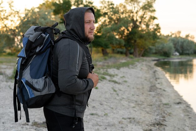 vue latérale du randonneur masculin avec sac à dos touristique debout au bord du lac,