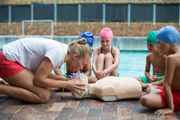 Vue latérale du sauveteur féminin démontrant les enfants au cours de la formation de sauvetage