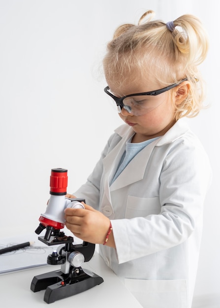 Vue latérale du tout-petit mignon avec microscope