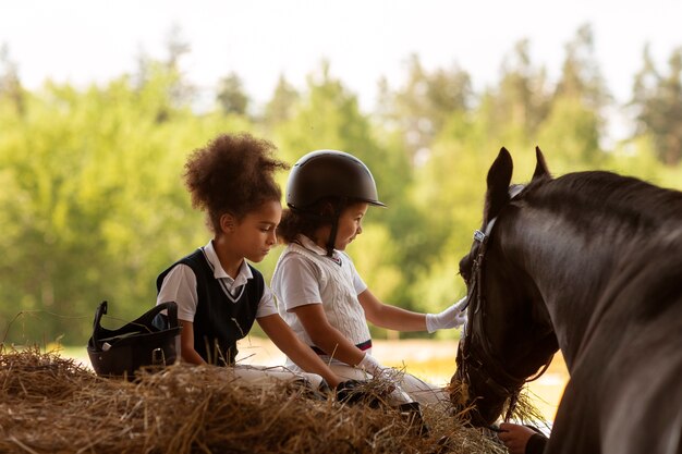 Photo vue latérale des enfants apprenant à monter à cheval