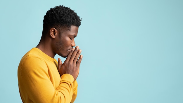 Photo vue latérale de l'espace de copie du jeune homme afro-américain en prière