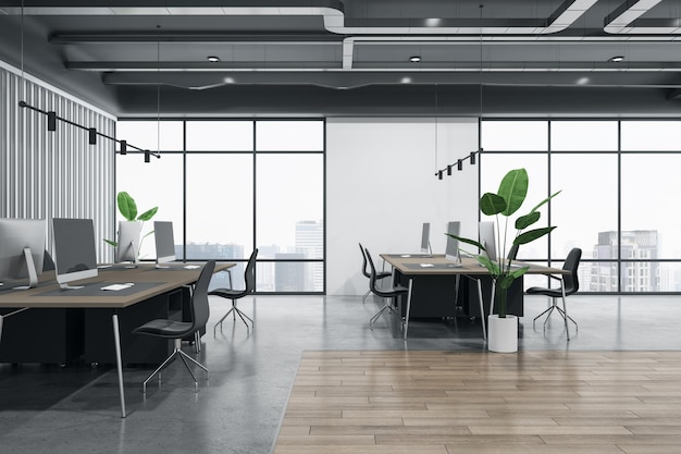 Vue latérale sur les espaces de travail dans un bureau de coworking avec vue sur la ville depuis de grandes fenêtres au sol en bois et en béton plantes vertes et ordinateurs modernes sur des tables marron rendu 3D