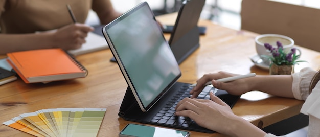 Vue latérale d'une étudiante tapant sur le clavier de la tablette tout en faisant l'affectation de groupe