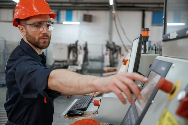 Vue latérale de l'exploitation de la machine L'ouvrier de l'usine est à l'intérieur avec un casque