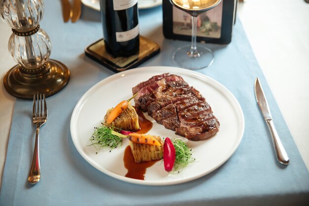 Vue latérale sur le faux-filet de boeuf grillé coupé avec pommes de terre sur plaque blanche