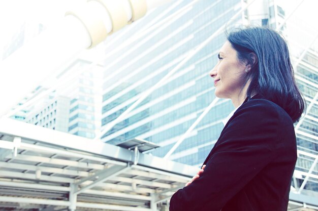 Vue latérale d'une femme d'affaires souriante debout dans la ville