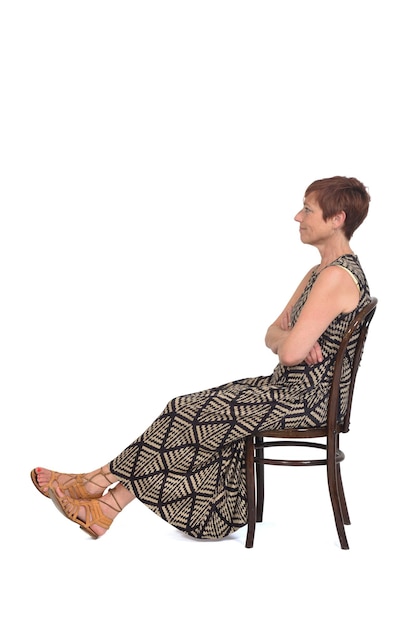 Vue latérale d'une femme d'âge moyen assise sur une chaise avec les jambes tendues sur fond blanc