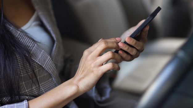 Vue latérale de la femme à l'aide de smartphone dans ses mains dans sa voiture alors qu'elle était coincée au feu de circulation