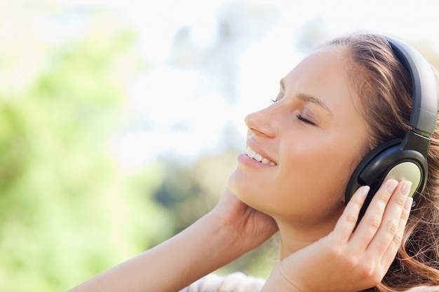 Vue latérale d&#39;une femme appréciant la musique dans le parc