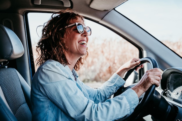 Photo vue latérale d'une femme assise au volant d'une voiture