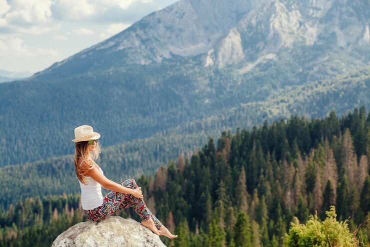 Photo vue latérale d'une femme assise sur un rocher contre une montagne