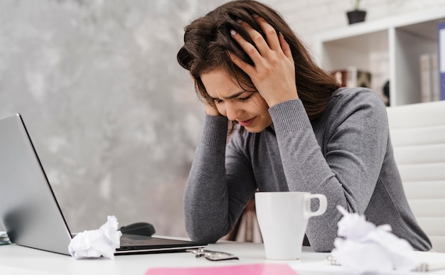 Vue latérale femme ayant mal à la tête tout en travaillant à domicile