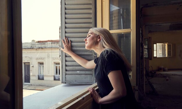 Photo vue latérale d'une femme debout contre la fenêtre