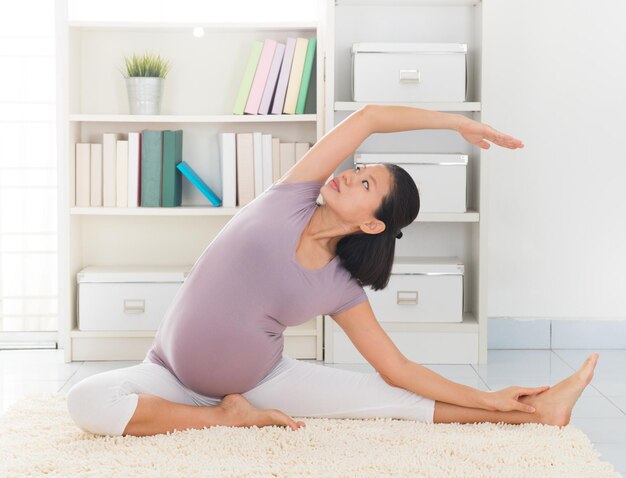 Photo vue latérale d'une femme enceinte faisant du yoga à la maison